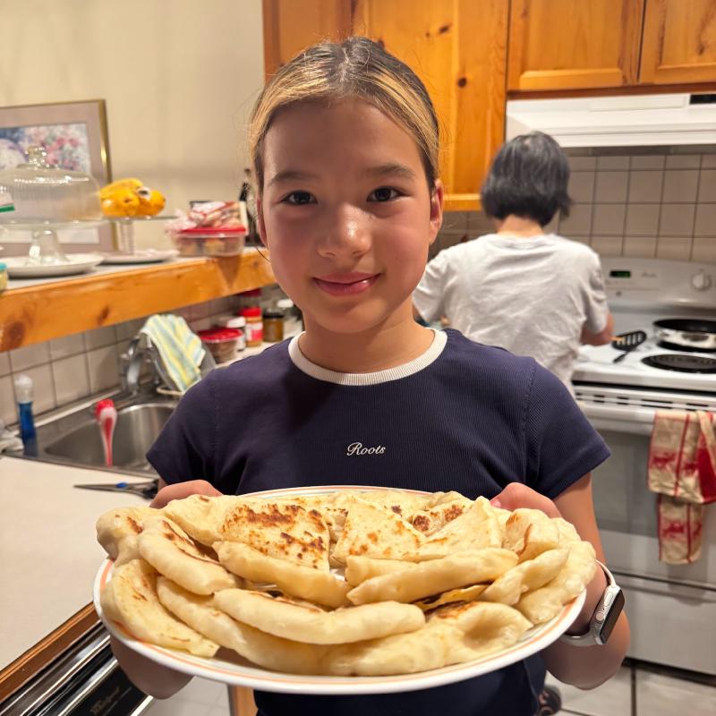 Camille holding a big plate of homemade naan in Grandma&rsquo;s kitchen